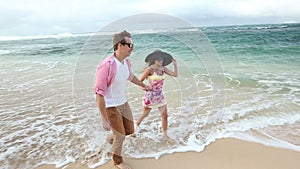 Loving young Caucasian couple holding hands walking together beach Oahu Hawaii