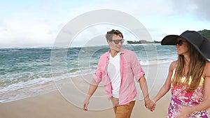 Loving young Caucasian couple holding hands walking together beach Oahu Hawaii