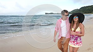 Loving young Caucasian couple holding hands walking together beach Oahu Hawaii