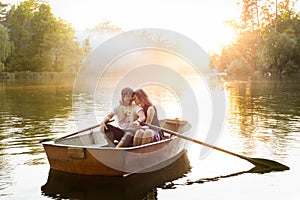 Loving young couple in boat at lake having romantic time.