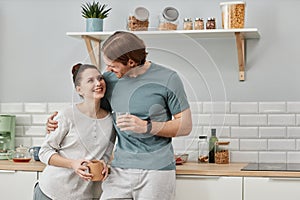 loving young couple embracing in kitchen and looking at each other