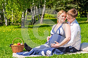 Loving young couple expecting a baby, rest on a picnic