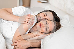 Loving young couple having cozy morning, cuddling together in their sleep on bed