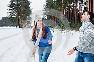 Loving young couple having fun in winter forest .