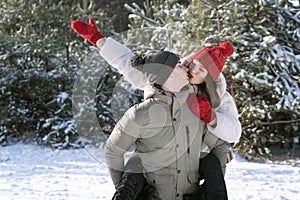 Loving young couple is having fun in winter outdoors. Guy rolls girl on his back