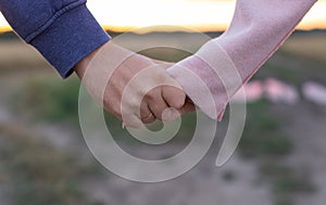 A loving young couple holding hands. Hands of a girl and a guy close-up. On a date boy and girl on the nature