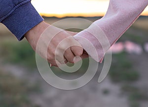 A loving young couple holding hands. Hands of a girl and a guy close-up. On a date boy and girl on the nature