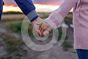 A loving young couple holding hands. Hands of a girl and a guy close-up. On a date boy and girl on the nature