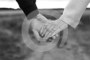 A loving young couple holding hands. Hands of a girl and a guy close-up. On a date boy and girl on the nature