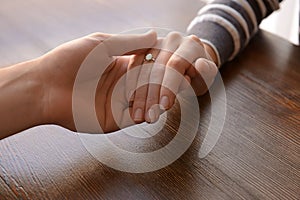 Loving young couple holding hands at table, closeup