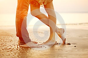 A loving young couple hugging and kissing on the beach at sunset