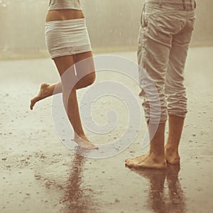 A loving young couple hugging and kissing under a rain. Lovers m