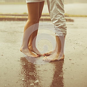 A loving young couple hugging and kissing under a rain. Lovers m