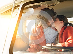 Loving young couple kissing in campervan during roadtrip