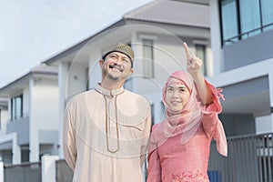 Loving young couple looking at dream house. Portrait of an excited Muslim couple standing outside their new home, walking on the