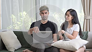 Loving young couple relaxing on sofa and surfing internet with computer laptop together