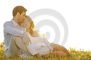 Loving young couple sitting on grass against clear sky