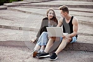 Loving young couple sitting on a walk with laptop