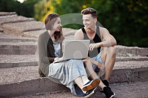 Loving young couple sitting on a walk with laptop