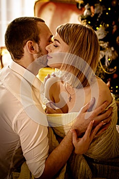 Loving young couple spends Christmas at home near a decorated, festive Christmas tree. Man and woman are happy spending