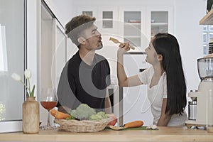 Loving young couple standing in kitchen and preparing ingredients for making fresh vegetable salad together. Healthy lifestyle,