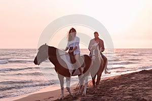 a loving young couple in summer clothes riding a horse on a sandy beach at sunset. Sea and sunset in the background