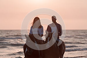 a loving young couple in summer clothes riding a horse on a sandy beach at sunset. Sea and sunset in the background