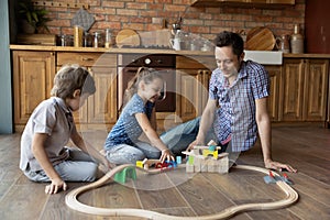 Loving young dad and two kids constructing railroad of bricks