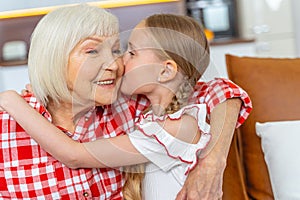 Loving young lady kissing her happy grandmother