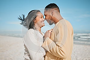 Loving young mixed race couple touching noses while dancing on the beach. Happy young man and woman in love enjoying