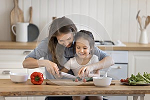 Loving young mother teach to cook her little adorable daughter