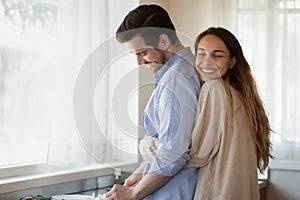 Loving young newlyweds cuddle cooking at home together photo