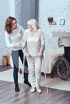 Loving young woman helping disabled old lady at home