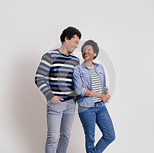 Loving young woman and man looking at each other romantically while standing on white background