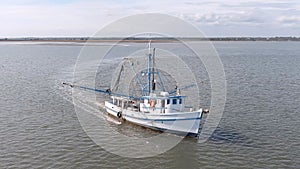 Low aerial view of a shrimp boat pulling nets off the coast of South Carolina, USA
