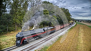 Low Aerial View of a Streamlined Antique Steam Freight Train, Blowing Black Smoke and Steam