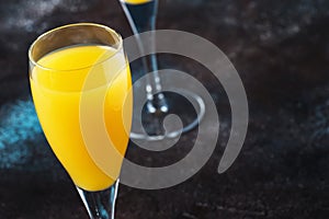 Low alcohol cocktail mimosa with orange juice and cold dry champagne or sparkling wine in glasses, blue background with flowers,