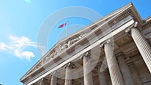 Low angle 4K footage of the entrance of the British Museum with the United Kingdom flag waving in London, England, UK
