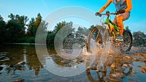 LOW ANGLE: Active man riding his mountain bike and splashing refreshing water.
