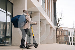 Low-angle back view of unrecognizable female courier food delivery with big thermal backpack walking with electric