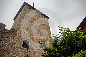 Low angle of beautiful tower with top of lush tree in chateau de chillon, castle in Montreux Switzerland, on cloudy sky background