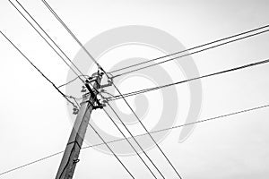 Low Angle Black and White Image of a Concrete Utility Power, Electricity Pole with Insulators and Cables