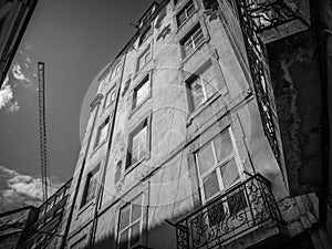 Low angle black and white shot of an old apartment building and a construction crane
