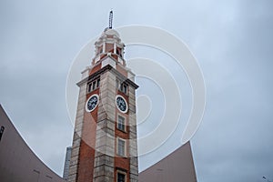 Low angle of clock tower in commercial district on overcast sky background