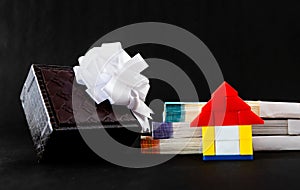 Low angle close up of a toy home, money, and gift box showing gifting house concept