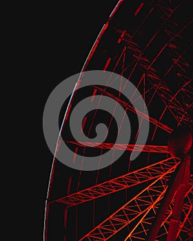 Low angle closeup shot of rotating Ferris wheel details with red lights at night