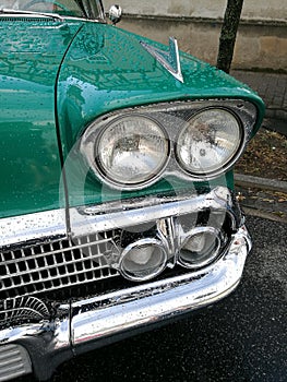 Low angle closeup view of the headlights of an old vintage green car