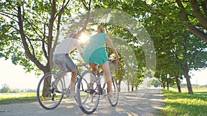 LOW ANGLE: Couple enjoys an active date by riding bikes down a sunlit avenue