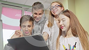 Low angle cropped shot of group of teens studying together, using laptop