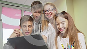 Low angle cropped shot of group of teens studying together, using laptop